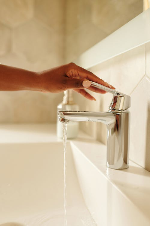 A person opening a tap with low water pressure
