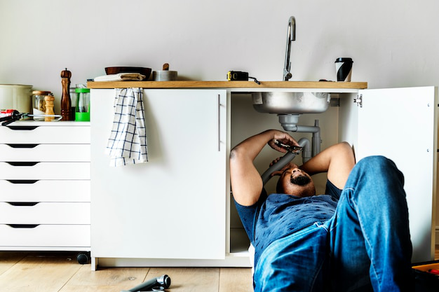 Plumber fixing a pipe under the sink