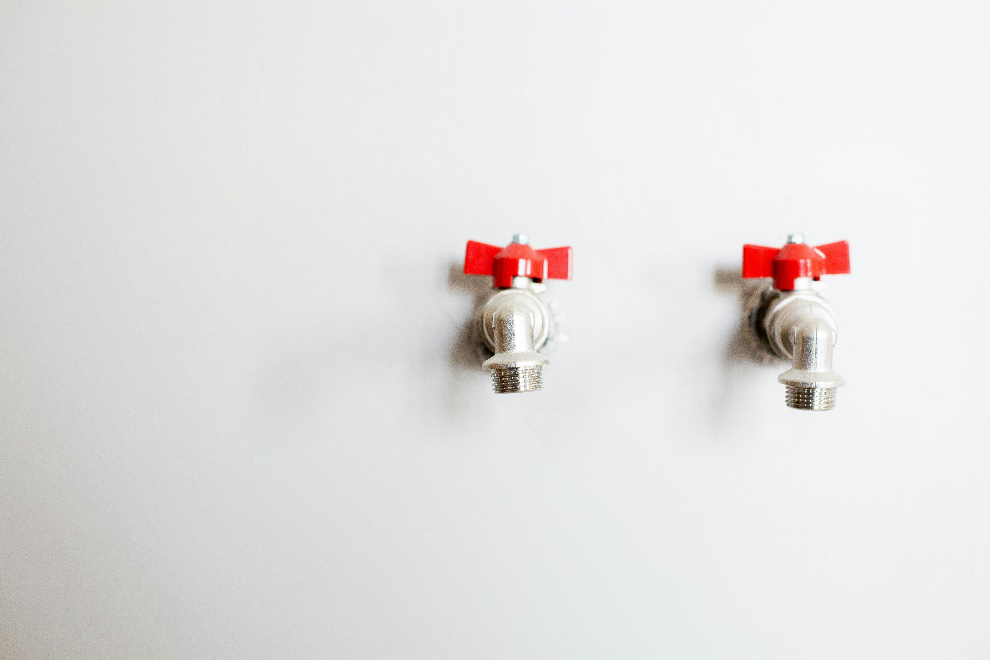 Two taps fixed on a beige wall