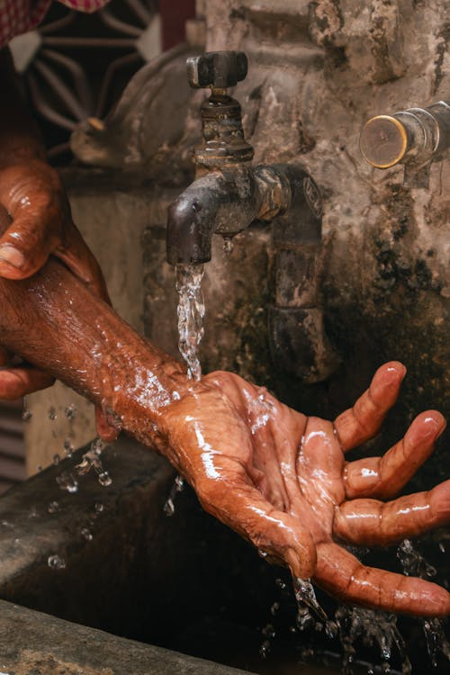 A person washing their hands with tap water.