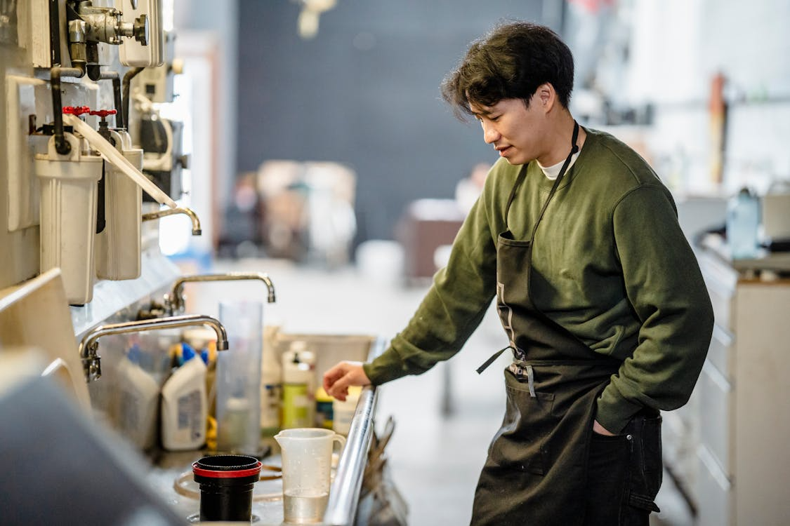 A person in an apron standing by the sink
