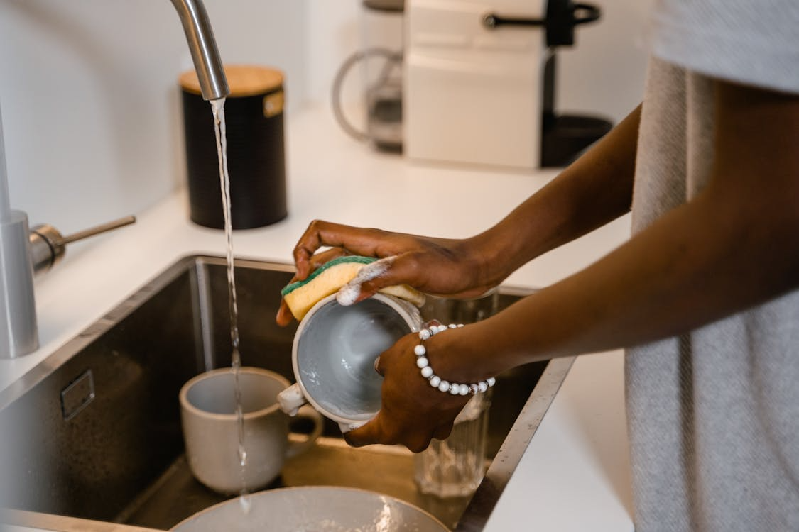 A person doing dishes in the sink