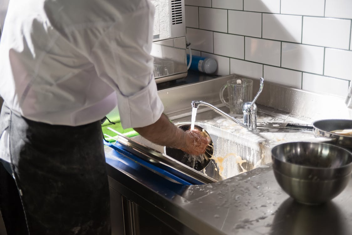 A person doing dishes in a commercial kitchen