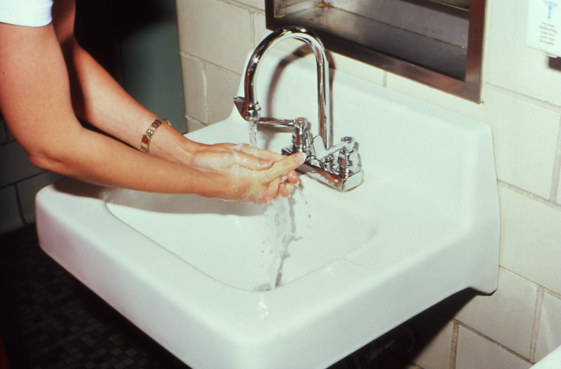 A person washing their hands on a sink