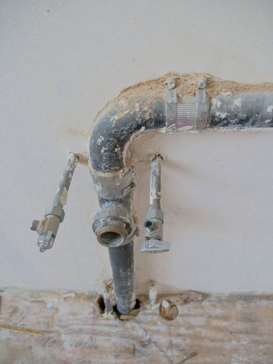 Metal plumbing pipes mounted along a wall showing signs of age and wear