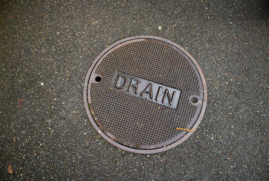 Round metal floor drain cover labeled drain