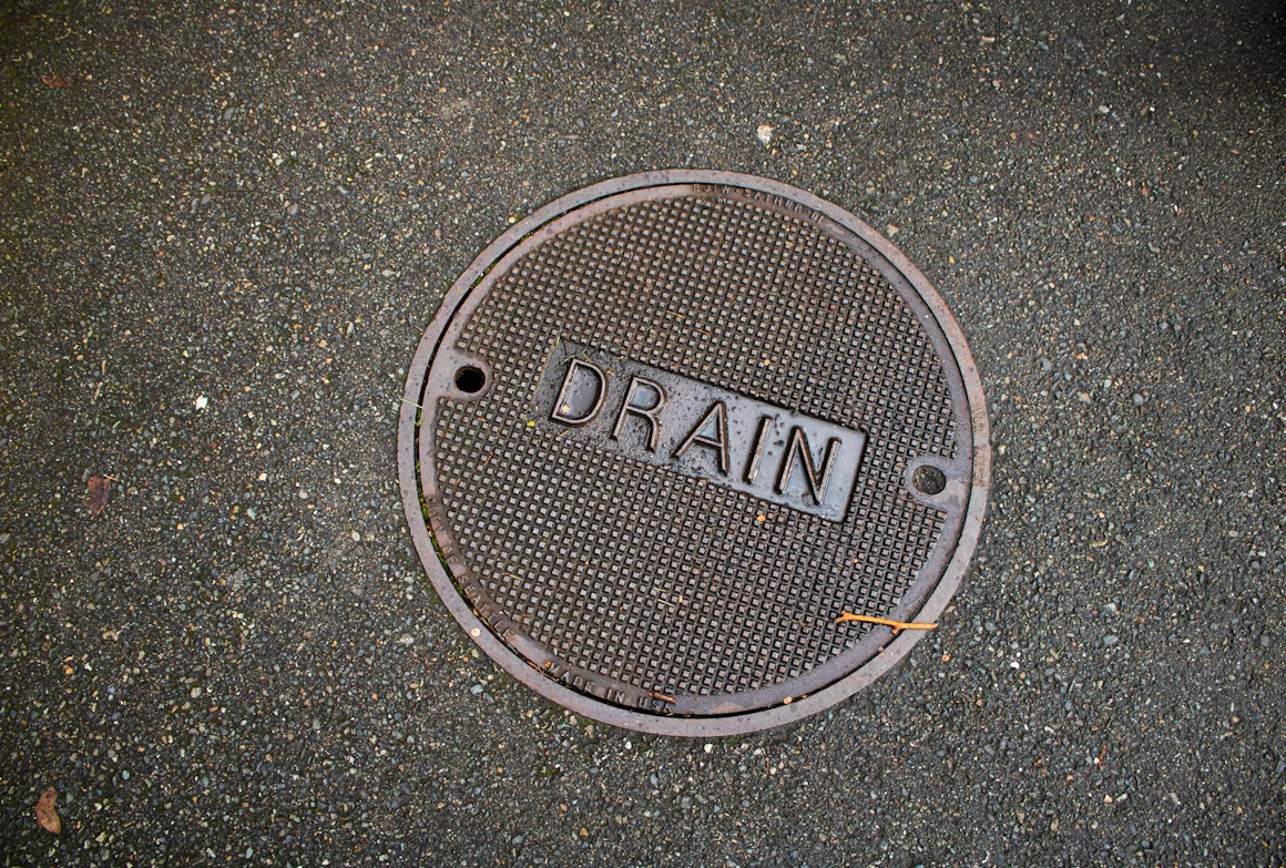 Round metal floor drain cover labeled drain