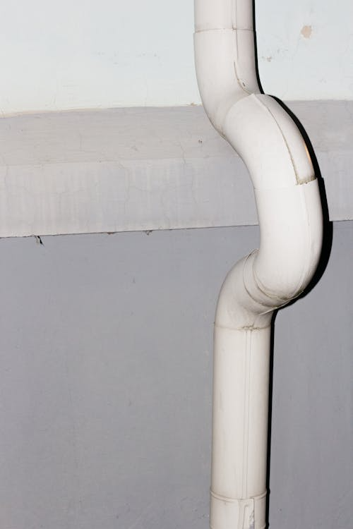 White exterior downspout attached to a concrete wall