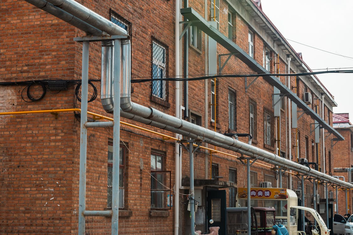 Exterior sewer pipes along an older commercial building.