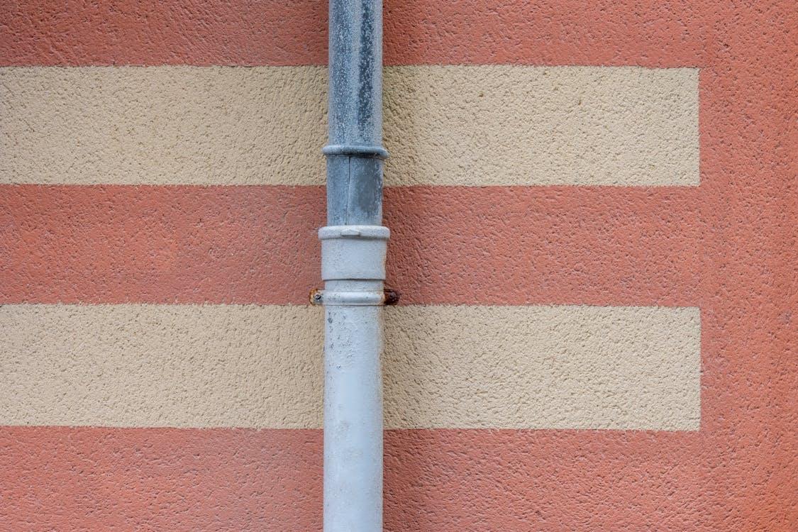 Close-up of a metal drainpipe running along a rustic wall