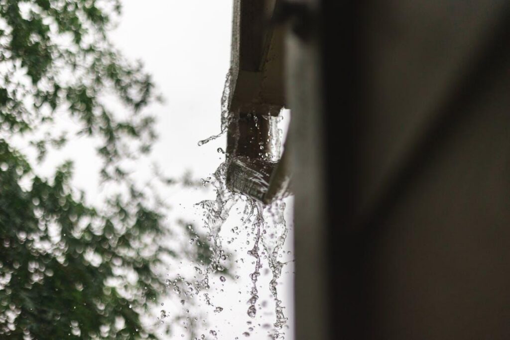 Rainwater overflowing from a clogged house gutter during a storm