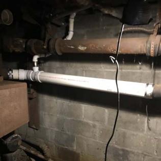 Exposed plumbing reveals aging pipe materials requiring repair or replacement.