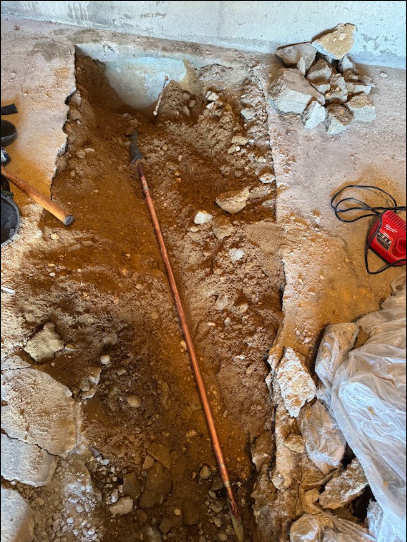 An underground supply line exposed during a leak repair, dug in dry summer ground.