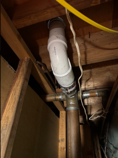 A waste line running between joists, the kind of run that carries odors when a trap or vent fails.