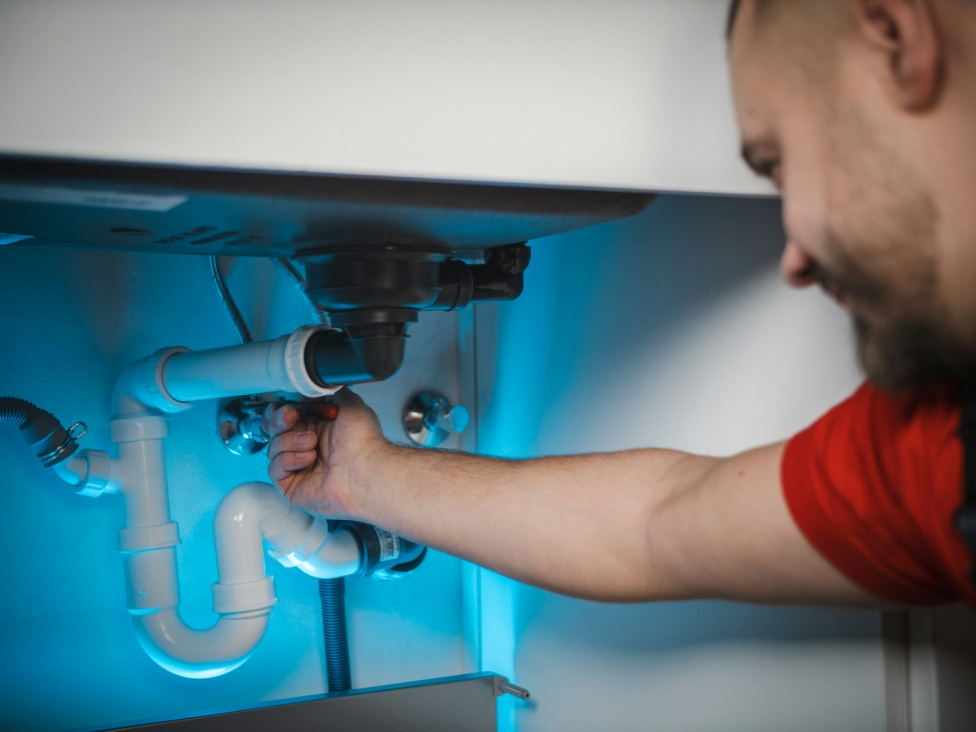 Professional plumber inspecting a residential plumbing drain system on Long Island